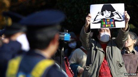 People protest against the proposed state secrets act in front of the parliament building as a policeman looks at in Tokyo