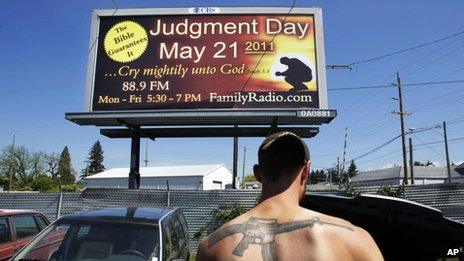 Mose Macdonald works in the impound yard of Stealth Recovery and Towing in Eugene, Oregon near a billboard proclaiming the upcoming judgment day 19 May 2011