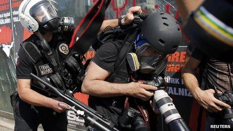 A Turkish riot policeman pushes a photographer during a protest at Taksim Square in Istanbul June 11, 2013