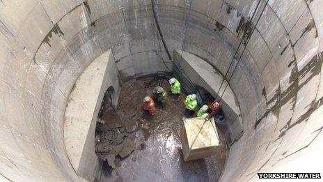 Workers in storm drain as tunnel machine breaks through