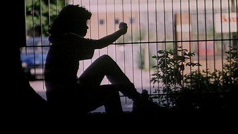 Silhouette of a girl looking through a park fence