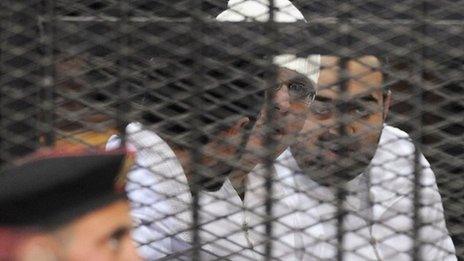 Political activists Ahmed Maher, Ahmed Douma (L) and Mohamed Adel (R) of the 6 April movement look on from behind bars in Abdeen court in Cairo, December 22, 2013.