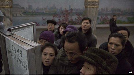 North Korean subway commuters gather around a public newspaper stand on the train platform in Pyongyang, North Korea to read the headlines about Chang Song-thaek, 13 December 2013