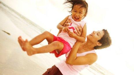 Woman holding young child on beach