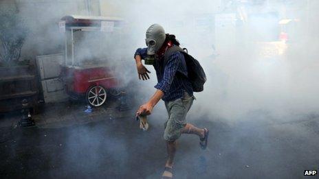 A demonstrator runs with gas mask as Turkish riot policemen use tear gas to disperse clashes on 31 May