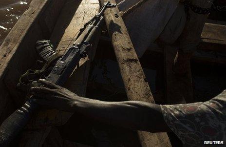 A man reaches for an AK47 assault rifle during a fishing expedition on Lake Turkana in north-western Kenya October 13