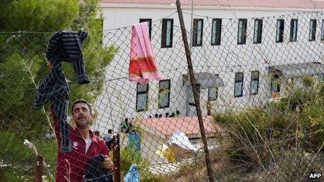 A man tries to dry his clothes one the fence of the migrant reception centre on Lampedusa (October 2013)