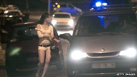 A prostitute approaches a car in Paris.