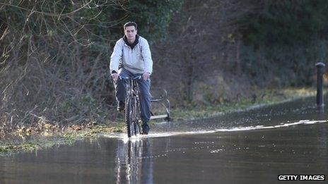 A man rides a bicycle through flood water