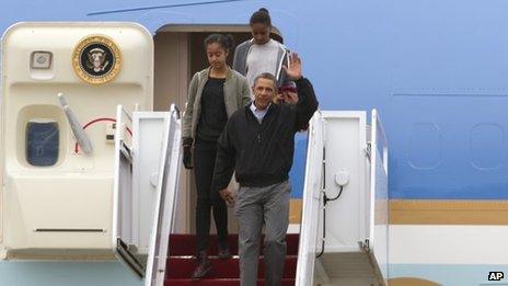 President Barack Obama accompanied by his daughters Malia and Sasha waves from Air Force One upon arrival at Andrews Air Force Base on 5 January 2014