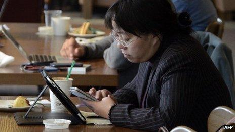 A woman using her phone and tablet PC in China