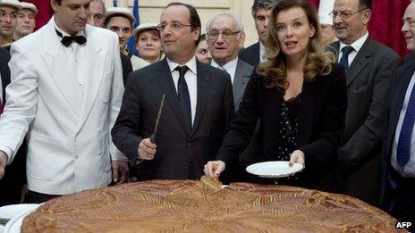 French President Francois Hollande (C) and his partner Valerie Trierweiler (3rd R) cutting slices of a traditional epiphany cake at the Elysee palace