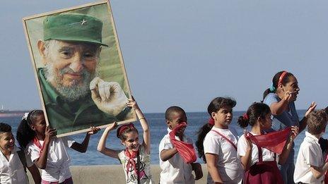 School children stand in Havana while holding a photograph of Cuba's former President Fidel Castro