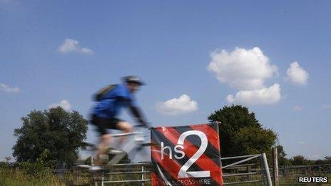 A man cycles past an anti high speed rail project (HS2) banner in Austrey, central England