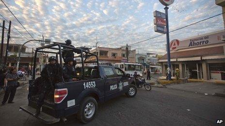 Federal police outside vandalised pharmacy in Apatzingan