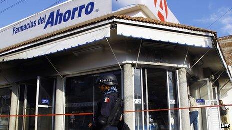 Mexican Federal Police members stand guard outside a drugstore that was attacked by organized crime gangs in Apatzingan,on 15 January, 2014