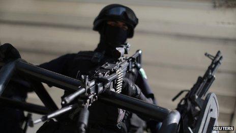 A federal police officer stands on the back of a police truck while loading fuel at a petrol station in Tepalcatepec on 15 January, 2014