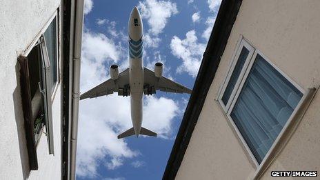 A passenger jet comes into land over houses near to London's Heathrow airport