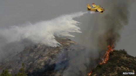 A "super scooper" air tanker makes waters drops as firefighters battle a fast-moving California wildfire, so-called the "Colby Fire", in the hills of Glendora 16 January 2014