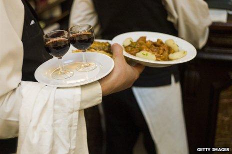 French waiter carrying wine and dinner