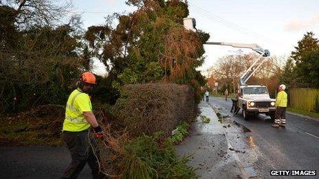 Workers remove fallen trees from powerlines in the village of Grafty Green in Kent on 30 December 2013