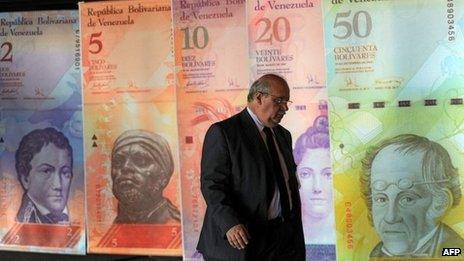 A man walk in front of posters of Venezuelan bills in Caracas