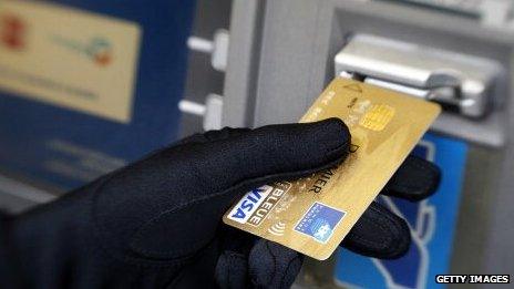 Sinister black-gloved hand inserting golden card into cash machine