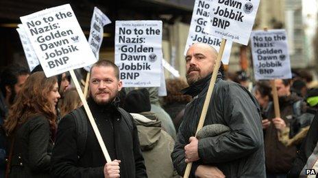 Unite Against Fascism protesters hold up placards saying: "No to the Nazis: Golden Dawn, Jobbik, BNP."