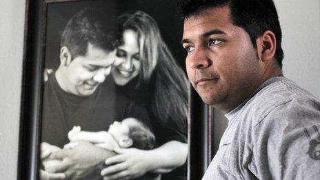 Erick Munoz stands with an undated copy of a photograph of himself with wife Marlise and their son Mateo, in Haltom City, Texas