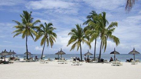 A sunny beach with sun loungers and palm trees