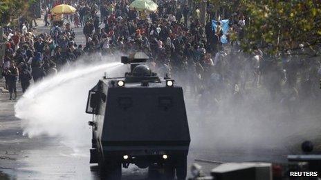 A police water cannon releases a jet of water on student protesters in Chile, April 2013