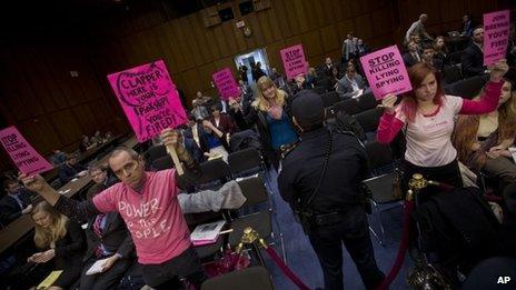 A Capitol Police officer monitors members of Code Pink as they hold up signs on Capitol Hill in Washington 29 January 2014