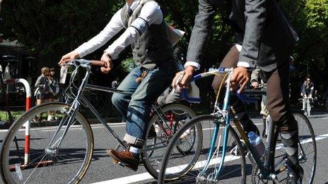 People wearing tweed jackets and pants cycle in Tokyo on 14 October 2013.