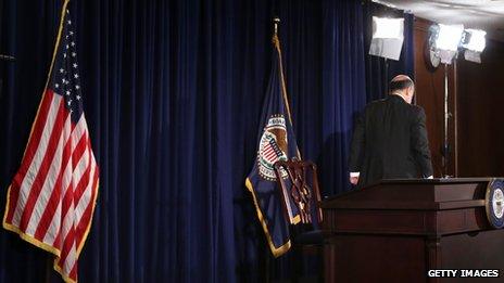 Ben Bernanke walking off a stage with a podium and flags