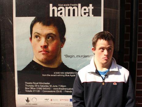 Tommy Jessop stands next to a poster of the play