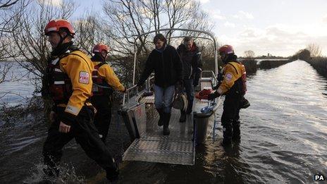 People disembark a fire and rescue boat used to ferry residents backwards and forwards to the flood-stricken Somerset village of Muchelney