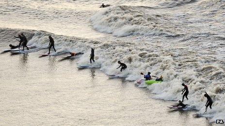 Surfers, kayakers and wave-skiers ride the tidal Severn Bore as it passes Newnham, Gloucestershire on 2 February