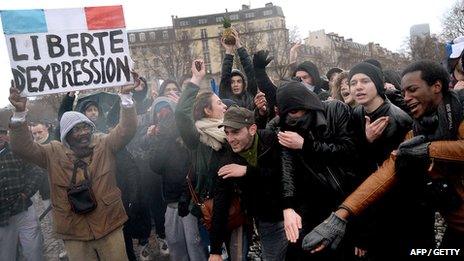 A man holds a placard reading "Freedom fo speech" as people perform the "quenelle" gesture, popularised by a French controversial comedian, during a demonstration called by the Collective "Day of Anger", supported among others by the conservative Printemps Francais