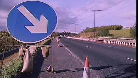 Roadworks sign and traffic cone on road