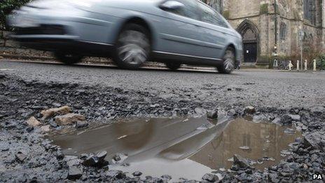 A car drives past a pothole on the road