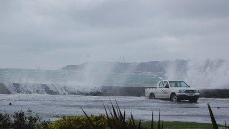 Waves crashing over wall onto car