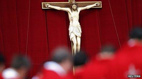 Priests stand in front of a crucifix. File photo