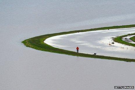 Man and dog walk on swollen bank