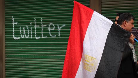 Protester with Egyptian flag by "twitter" graffiti, Tahrir Square 2011