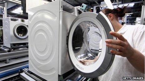 A factory worker assembles a washing machine