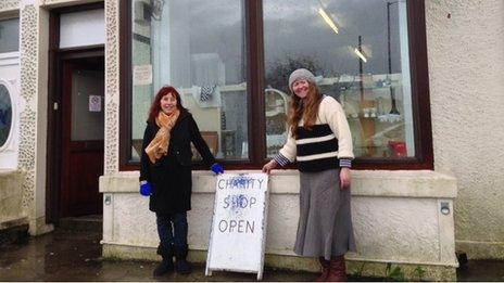 Two women stand outside a charity shop