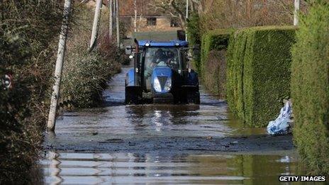 A tractor drives down a flooded road