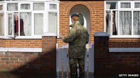 A British army soldier speaks to an Egham resident whose house is surrounded by flood water