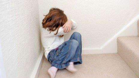 Young girl covering her face in a corner