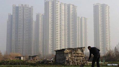 A farmer shovels soil at a vegetable field near a new residential compound on the outskirts of Wuhan